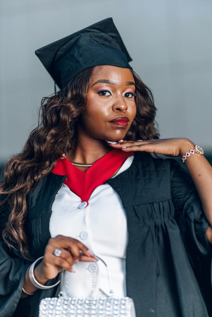 Confident graduate posing in cap and gown indoors, symbolizing achievement and success.